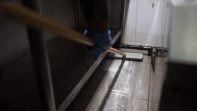 A person wearing blue gloves is diligently scrubbing the tiled floor of an industrial kitchen, ensuring thorough cleanliness and hygiene in the workspace. - Powered by Shutterstock - Get 15% off with code: PIKWIZARD15