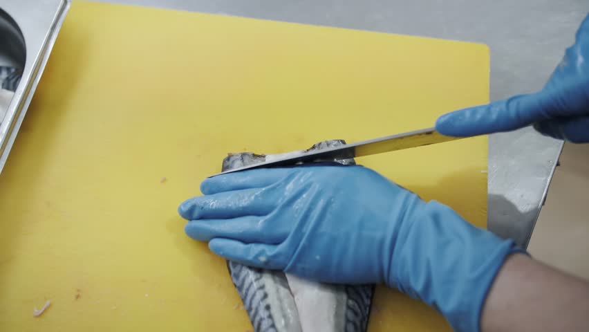  The cook cuts the herring fish fillet into even slices on a cutting board