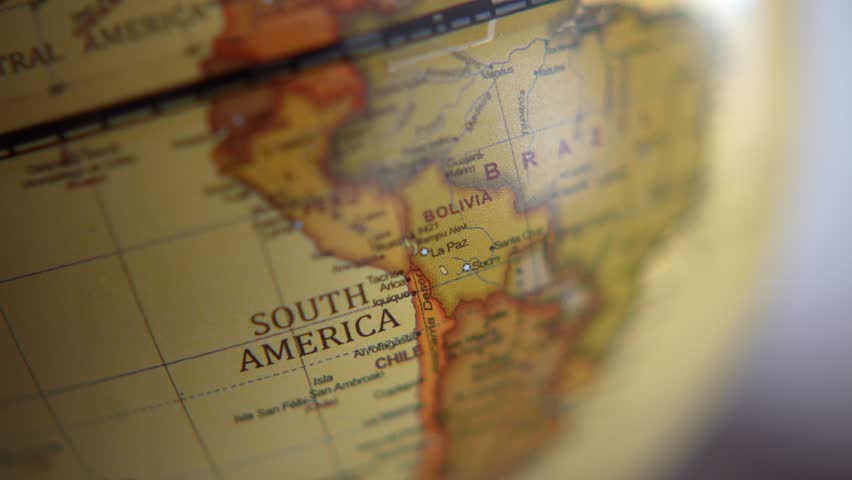 Vintage world globe on wooden table with soft natural light and shallow depth of field. Close-up of antique styled earth globe showing South America, symbolizing travel, geography, global business, education, and exploration concepts.