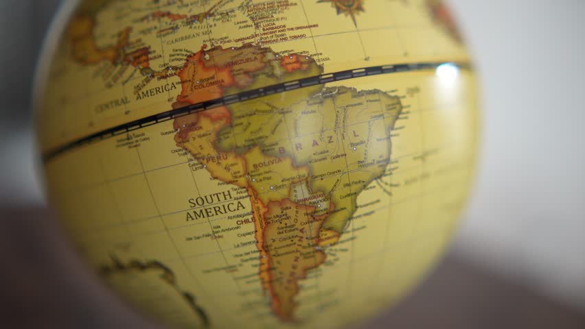 Vintage world globe on wooden table with soft natural light and shallow depth of field. Close-up of antique styled earth globe showing South America, symbolizing travel, geography, global business, education, and exploration concepts.