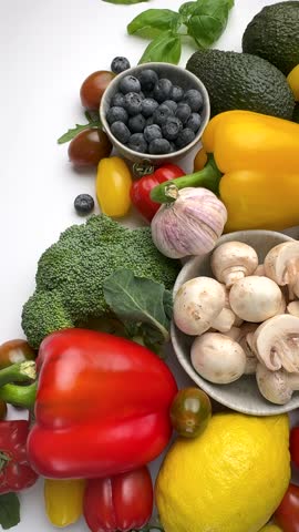 Assortment of fresh healthy raw fruits and vegetables rotating on a clean white background