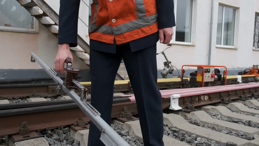 Man in an orange vest Railway Worker Measuring Track Gauge