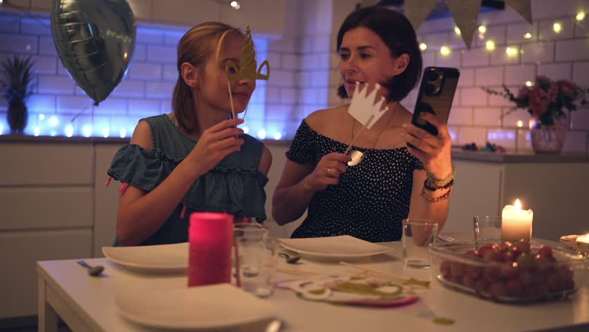 Happy Mother And Daughter In Party Outfits With Golden Crowns Taking Selfie