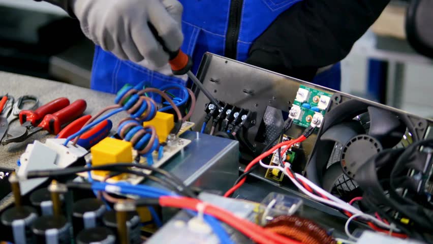 Technicians working on complex electronic components in a high-definition setting with detailed close-ups of tools and equipment