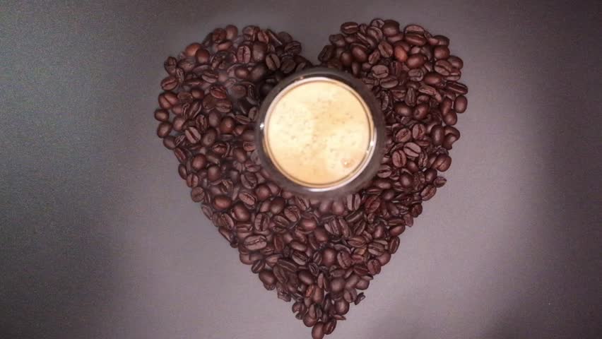 Hand reaching for coffee cup in heart of beans