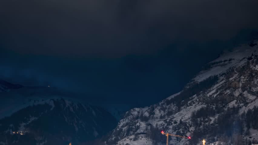 Timelapse over Zermatt in Switzerland at night. Swiss ski resort. The Matterhorn in the background during starry night with Orion constellation visible over the Matterhorn. Famous alpine village.