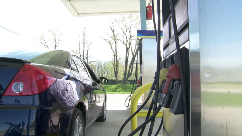 Young man buys regular gas at a self-service gas station.  Camera moves on jib.