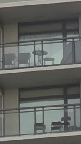 Richmond BC 02.17.2026.  High-angle view from a modern glass balcony overlooking a dense urban skyline with high-rise apartment towers and a harbor under an overcast sky.