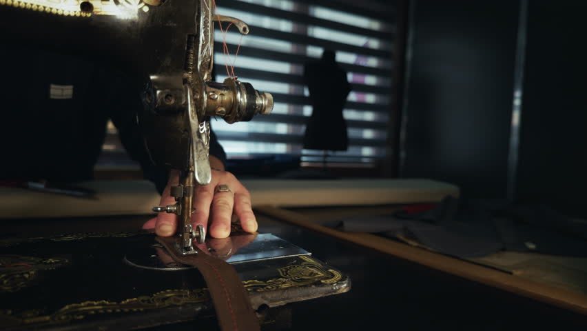 Close up view of a vintage golden tailor sewing machine in a workshop, highlighting classic craftsmanship, traditional tailoring tools, and detailed textile production process.
