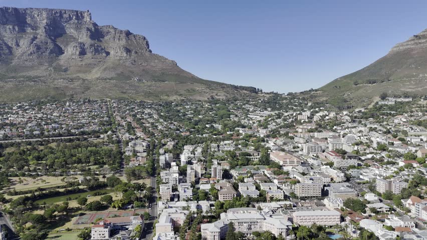 Drone flies backwards over City Bowl with view of Table Mountain on a clear morning in Cape Town, South Africa