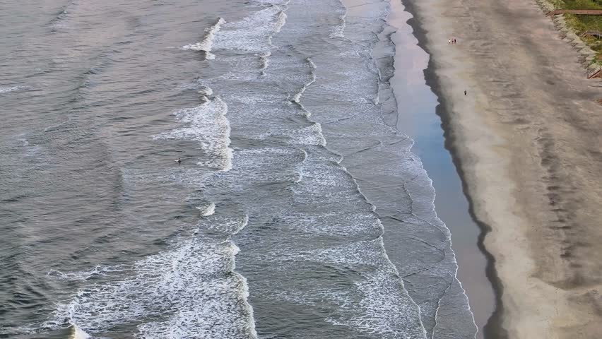 Panoramic aerial view of Folly Beach near Charleston, South Carolina landscape showing beach and ocean waves during morning sunrise with people enjoying the shore - 4K Drone