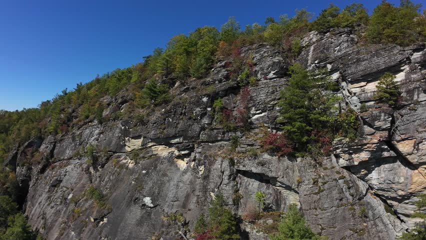 Majestic Cliff With Pine Pockets. Imposing Vertical Face With Steep Drop Into Wooded Valley. Dramatic Natural Formation Showcasing Layered Rocks And Dense Forested Surroundings
