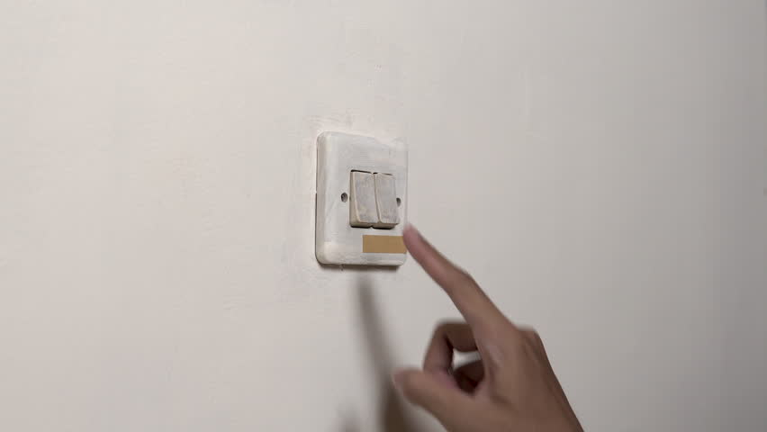 Close-up hand flips a wall light switch on and off, producing dry, sharp plastic clicks with a firm snap from finger pressure