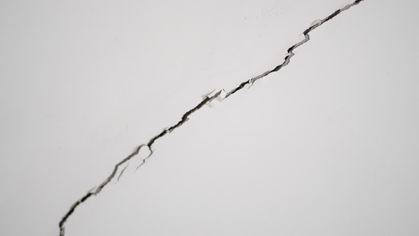 Large Diagonal Crack in White Concrete Wall or Ceiling Showing Structural Damage