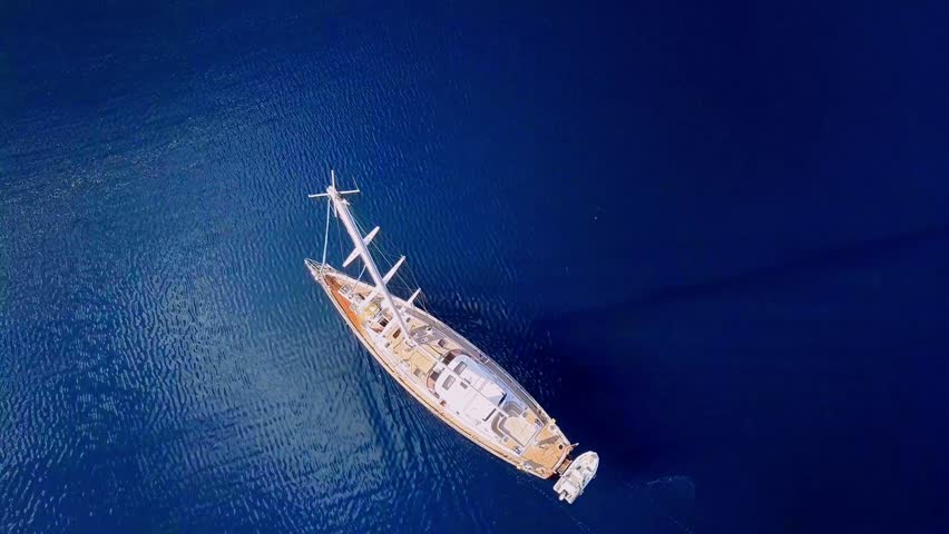 Aerial View of a Luxurious Sailing Yacht Gliding Through Calm Blue Sea Waters in Greece or Italy