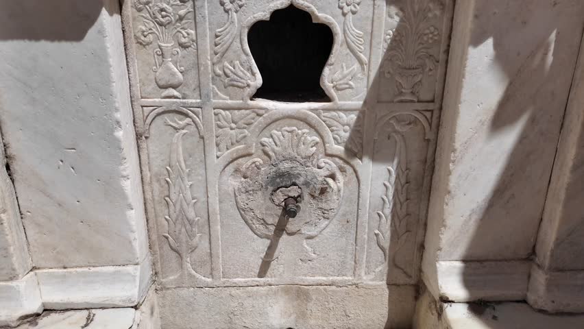 Paros Island,Tilt up of a historic fountain at Paroikia on a sunny day with front details of the marble fountain.