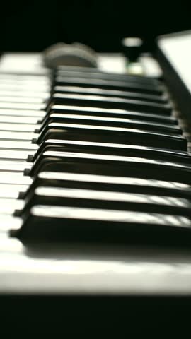 Close up pianist hands gracefully pressing keys synthesizer, creating music in softly lit studio with shallow depth of field artistic effect. Musician hands playing electronic piano keyboard. Vertical