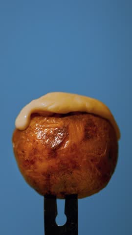 Raclette cheese dripping on a roasted baked potato, close-up up slow-motion video
