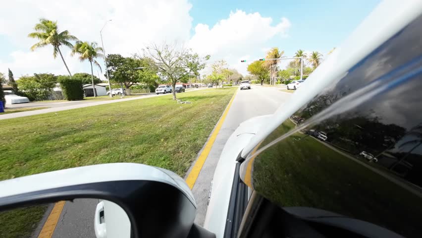 Car moving at speed along road divided by green grass median with trees. Urban transportation and travel concept.