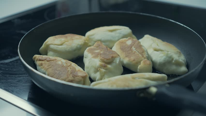 Close-up of pies being fried in a frying pan. Traditional cuisine. 4K.
