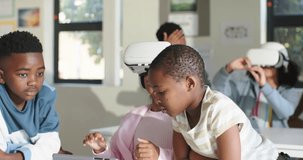 African American children leaning over tablet, helping student in VR headset in class, copy space. Classroom, edtech, collaboration, learning, touchscreen, virtual, reality - Powered by Shutterstock - Get 15% off with code: PIKWIZARD15