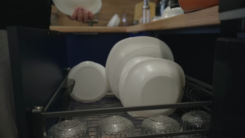 Woman Placing Clean Plates into Kitchen Storage Drawer