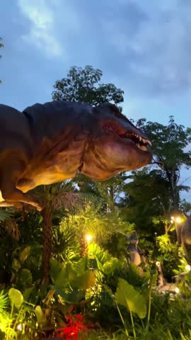 A dynamic dinosaur model in an outdoor park, captivating the audience as it moves its head and opens its mouth, adding a thrilling prehistoric element to the park