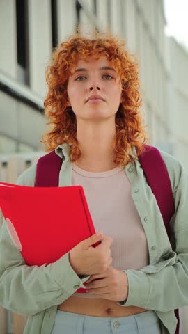 Determined young student grasping a red folder, embodying focus and ambition for upcoming academic challenges. A moment of concentration as they prepare to tackle their educational journey ahead.