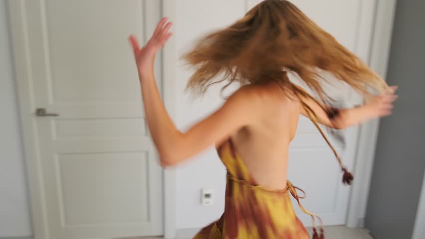 lively blonde woman dancing happily, carefree blonde woman joyfully twirling in bright apartment scene, an exuberant blonde woman dancing energetically and happily inside luminous apartment space