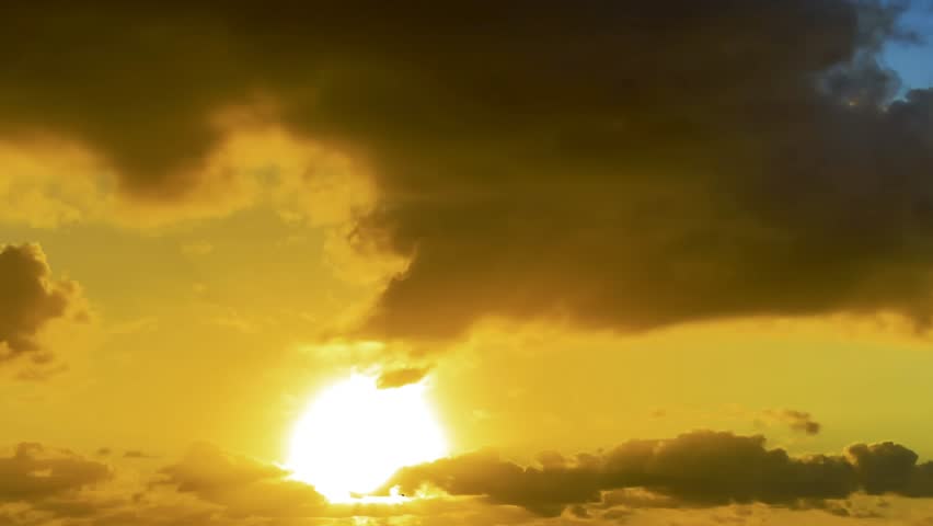 Dramatic golden sunset illuminating dark storm clouds in a glowing evening sky