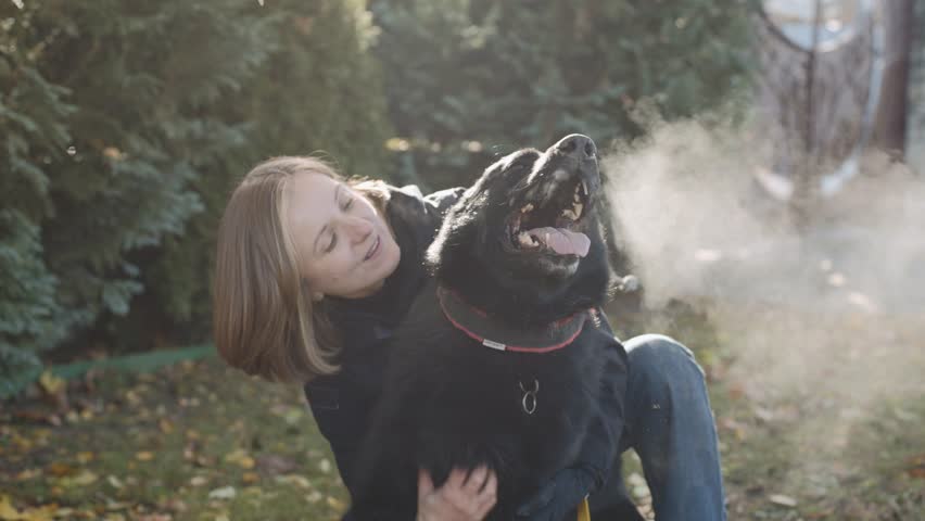 Girl plays with her dog in the yard during a cool day