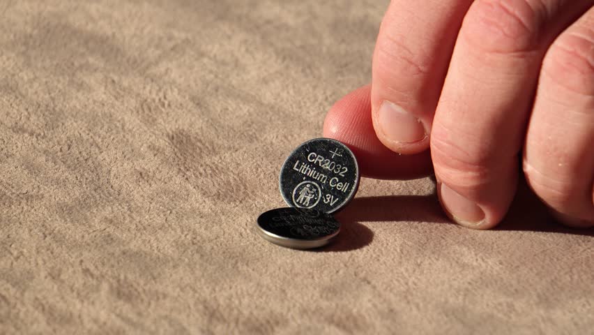 Lithium battery in hand. Button cell battery in hand, galvanic power cell.