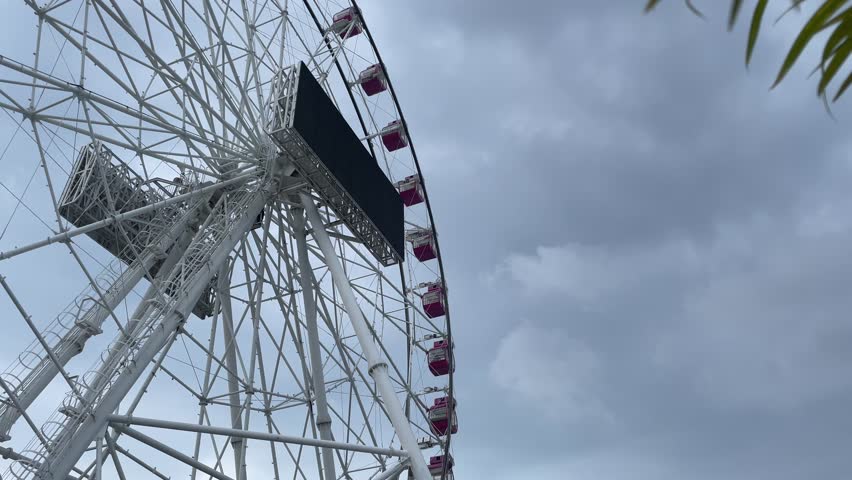 Giant White Ferris Wheel with Pink Gondolas and Digital Billboard Screen