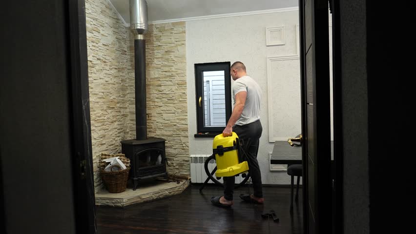 A man vacuums a room and dances, a man with a vacuum cleaner in his hands dances around the room while cleaning.