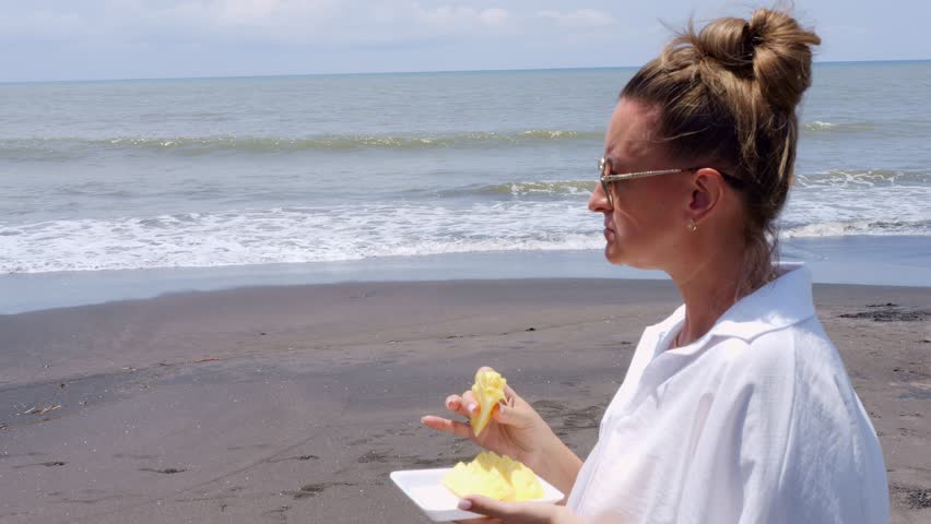 Tropical beach snack with woman enjoying fresh pineapple by sea Pineapple flavor reflects summer freedom pineapple refreshment matches ocean breeze pineapple moment captures healthy coastal lifestyle