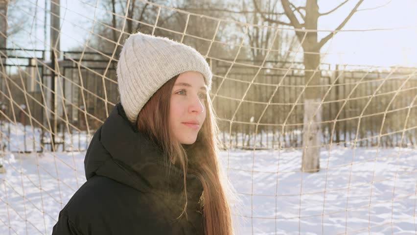 Portrait of a young beautiful girl in a hat with long hair on a snowy winter day