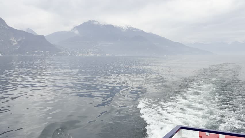 Wide panoramic view of lake and mountain peaks under clear sky. Natural reflections and tranquil landscape