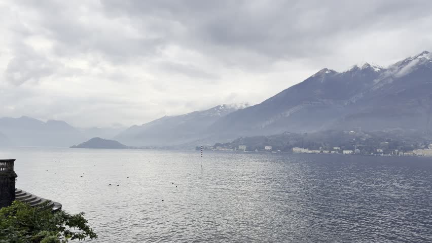 Wide lake with mountain range and dramatic peaks beneath clear sky. Calm reflections and natural harmony