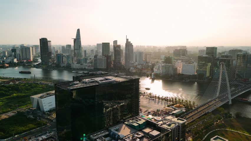 Aerial view of ho chi minh city skyline with saigon river, bridge, and modern skyscrapers at sunset, vietnam.