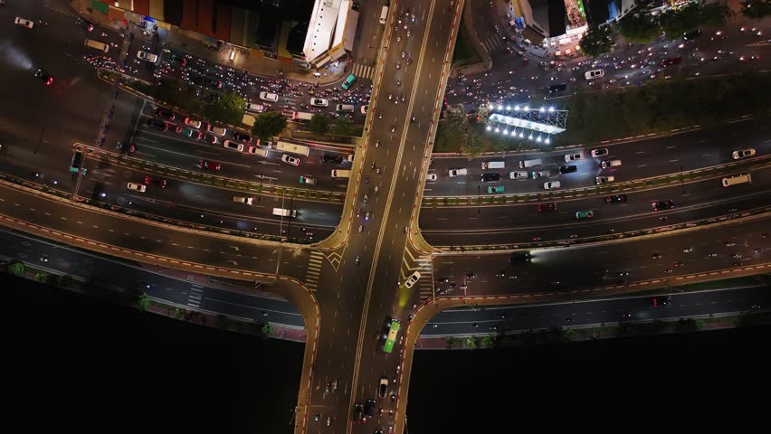 Aerial view of night traffic moving through a busy intersection and overpass in ho chi minh city, vietnam.
