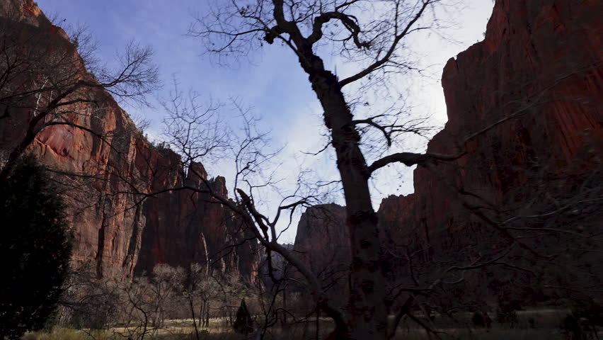 View from the vehicle driving down Zion canyon of Angels Landing as the sun peaks over the cliffs in Utah.