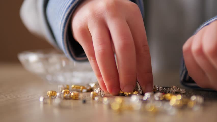 Child Collecting Gold and Silver Decorative Gems into Glass Vase 4k