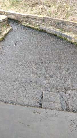 Water flowing through concrete canal channel in overcast daylight