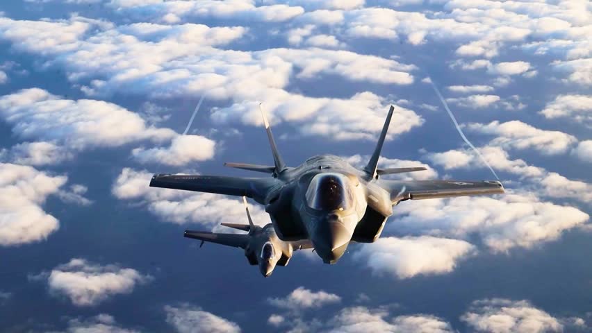 Two Advanced Stealth Fighter Jets F-35 Flying Above Clouds During High Altitude Strategic Formation Mission.