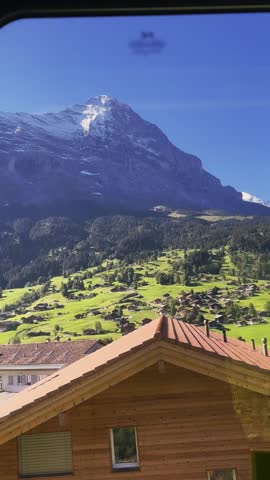 Scenic Train Ride in Grindelwald
View from a moving train passing green hills, alpine houses and snowy mountains in Switzerland.