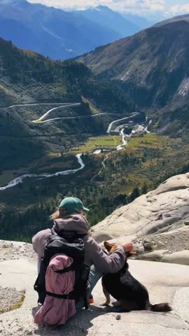 Man and Dog Overlooking Furka Pass Valley
Hiker sitting with his dog while admiring the breathtaking serpentine road and vast alpine valley of Furka Pass.