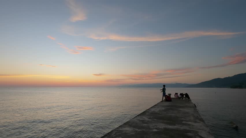 People on Pier at Sunset Over Ocean