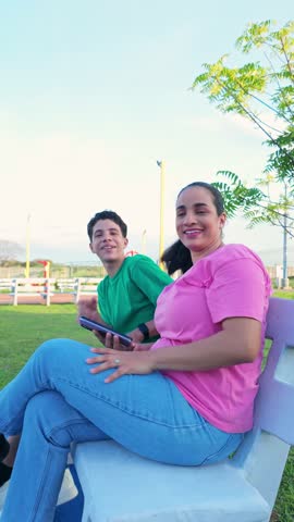 A woman and a man are sitting on a bench in a park