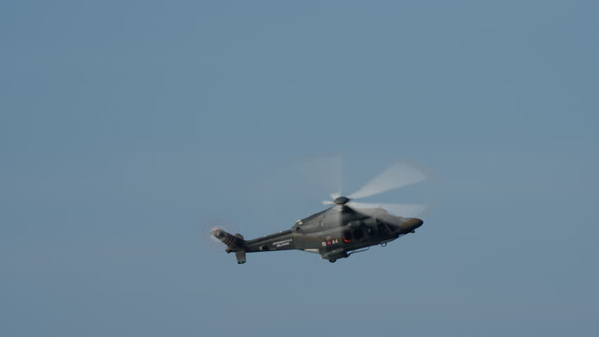 LUQA, MALTA - SEPTEMBER 28, 2025: An Armed Forces of Malta AgustaWestland AW139 military helicopter flies across a clear blue sky. The camera pans to follow the aircraft, showing its spinning main and