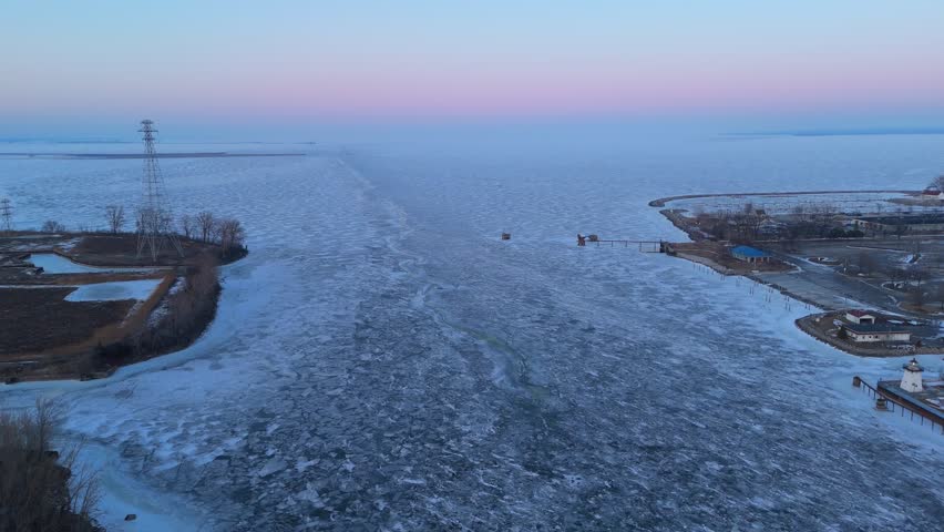 Aerial of Green Bay Wisconsin in Winter at Dusk.  Pull drone shot of frozen river and Lake Michigan.